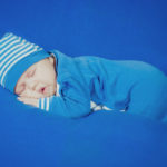 Photographie d'un bébé qui dort, en pyjama bleu.