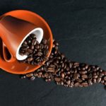 Photographie d'une tasse renversant des grains de café.