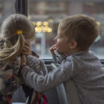 Photographie de deux enfants qui se taquinent dans un transport en commun.