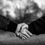 Photographie en noir et blanc de deux hommes qui se serrent la main.