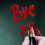 Photographie d'une écriture "Bye" au rouge à lèvres sur un miroir