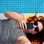 Photographie d'une femme allongée au bord d'une piscine, qui écoute de la musique.