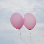 Photographie de deux ballons de baudruche dans le ciel.