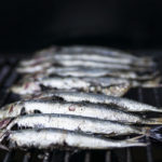 Photographie de sardines disposées sur une grille de barbecue.