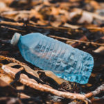 Photographie d'une bouteille en plastique posée sur la plage.