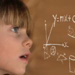 Photographie d'une fillette face à un tableau de formules mathématiques.